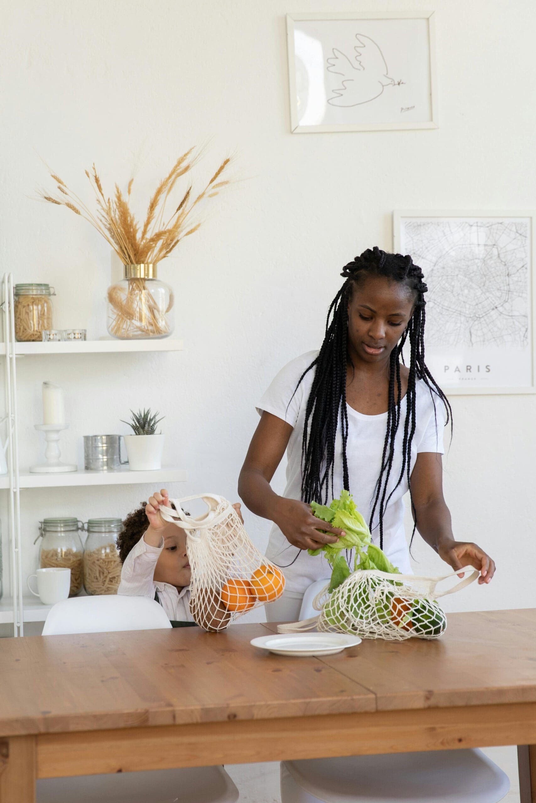 Woman and child in the kitchen unloading fresh produce from eco friendly grocery bags.