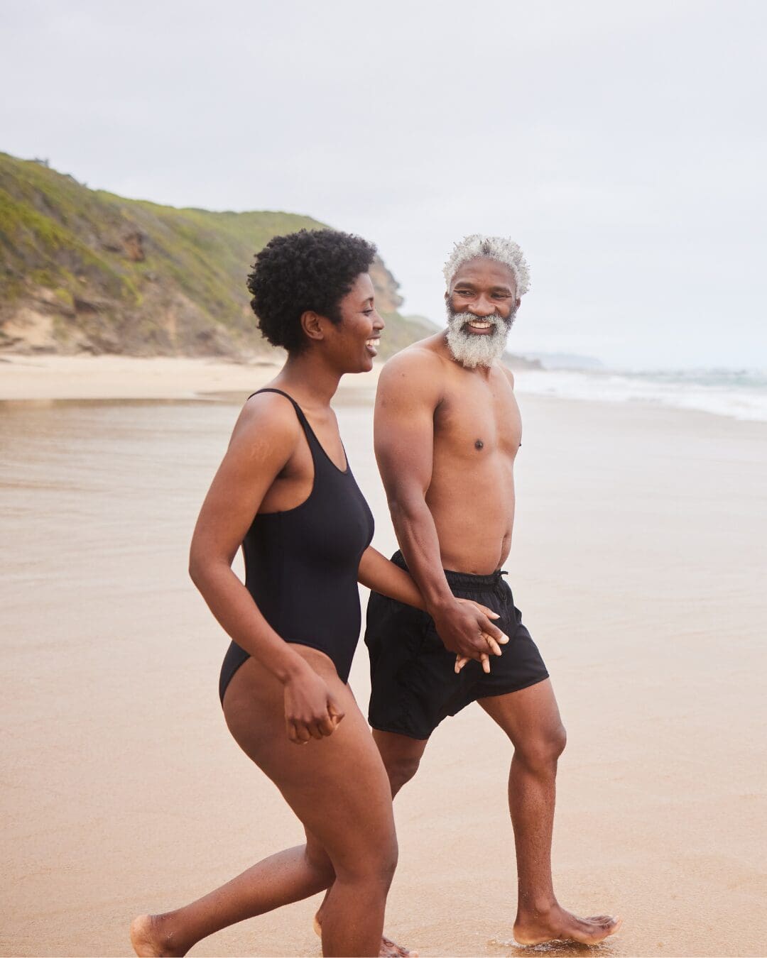 Man and woman walking hand in hand on the beach.
