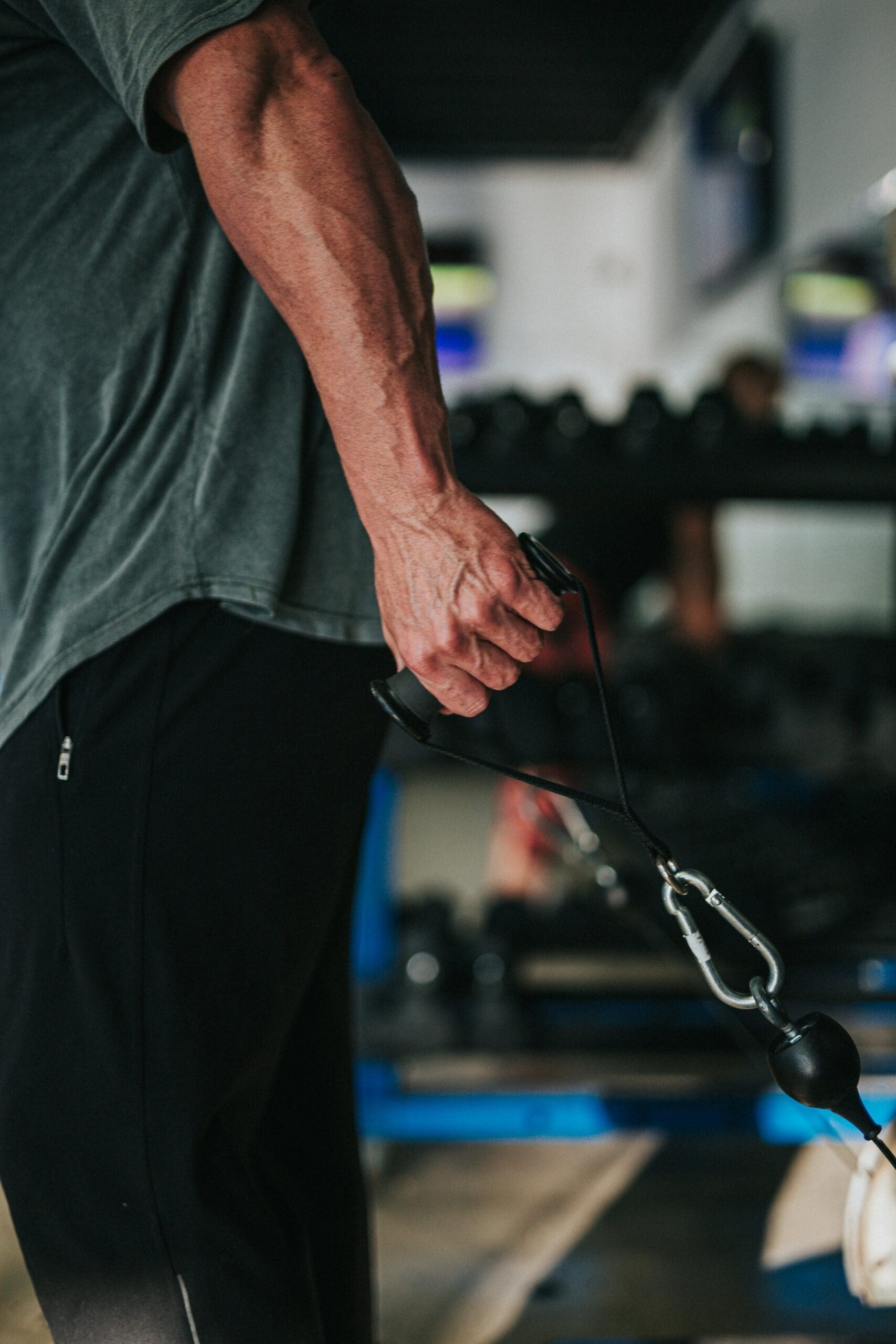 Close up of a man's hand pulling a band attached to a weight machine.